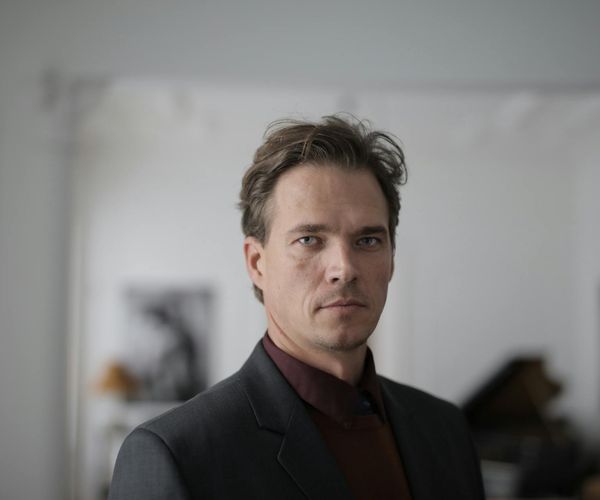 Man standing on a hill at sunrise, looking out with a determined expression.